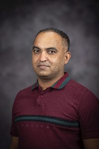 Man in burgundy shirt with a strip