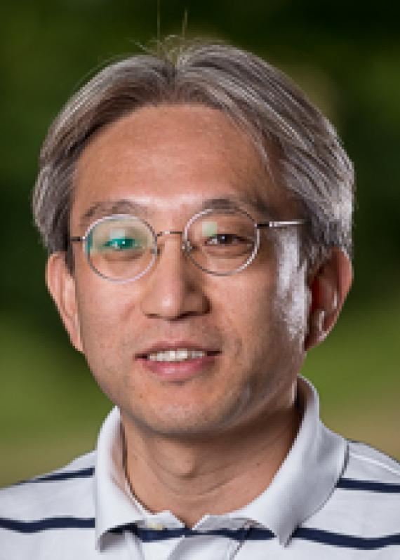Man with gray hair and glasses in which polo shirt with dark stripes